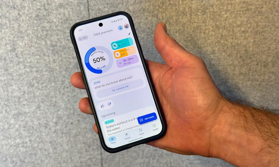 The redesigned Fitbit App on a Pixel phone held in mid-air, showing the home screen of the Today page. 